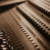 Close-up shot of a professional audio mixer with slide controls in warm lighting, showcasing analog audio technology.