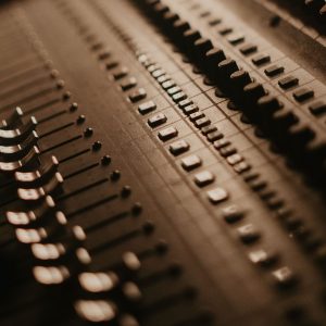 Close-up shot of a professional audio mixer with slide controls in warm lighting, showcasing analog audio technology.